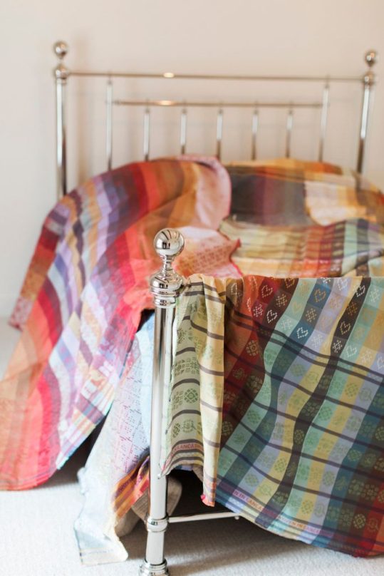 Folklore Fabrics draped over bed All Folkore Fabric designs are available in several glorious colourways.