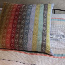 Folklore Fabric metered lengths in a Ecru colourway stitched into a cushion.